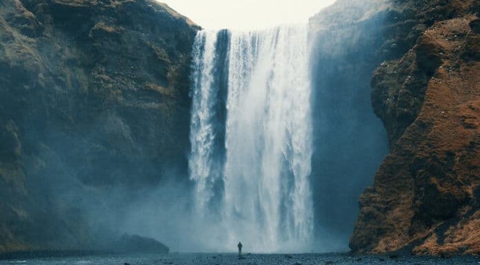 Skogafoss waterfall is imposing over a tourist